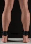Cavigliere BDSM Avanza Vantage 8 in ecopelle nera indossate, unite dal cinturino